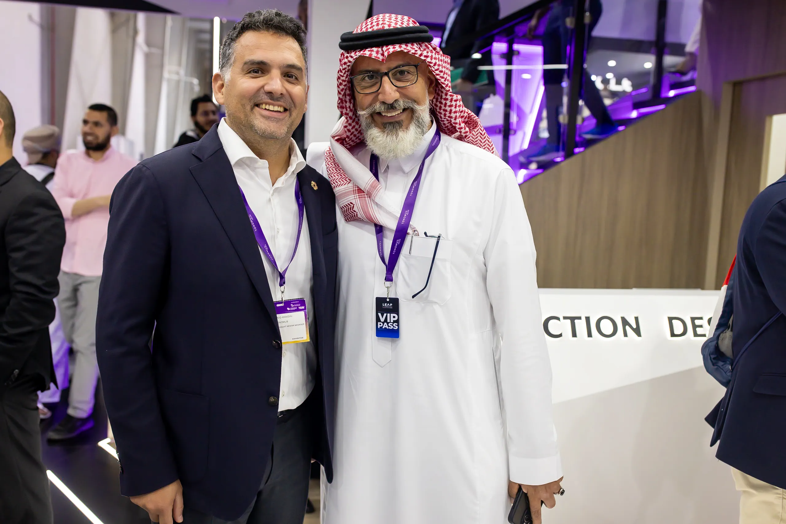 Two guests posing together at the stand, one wearing a VIP pass