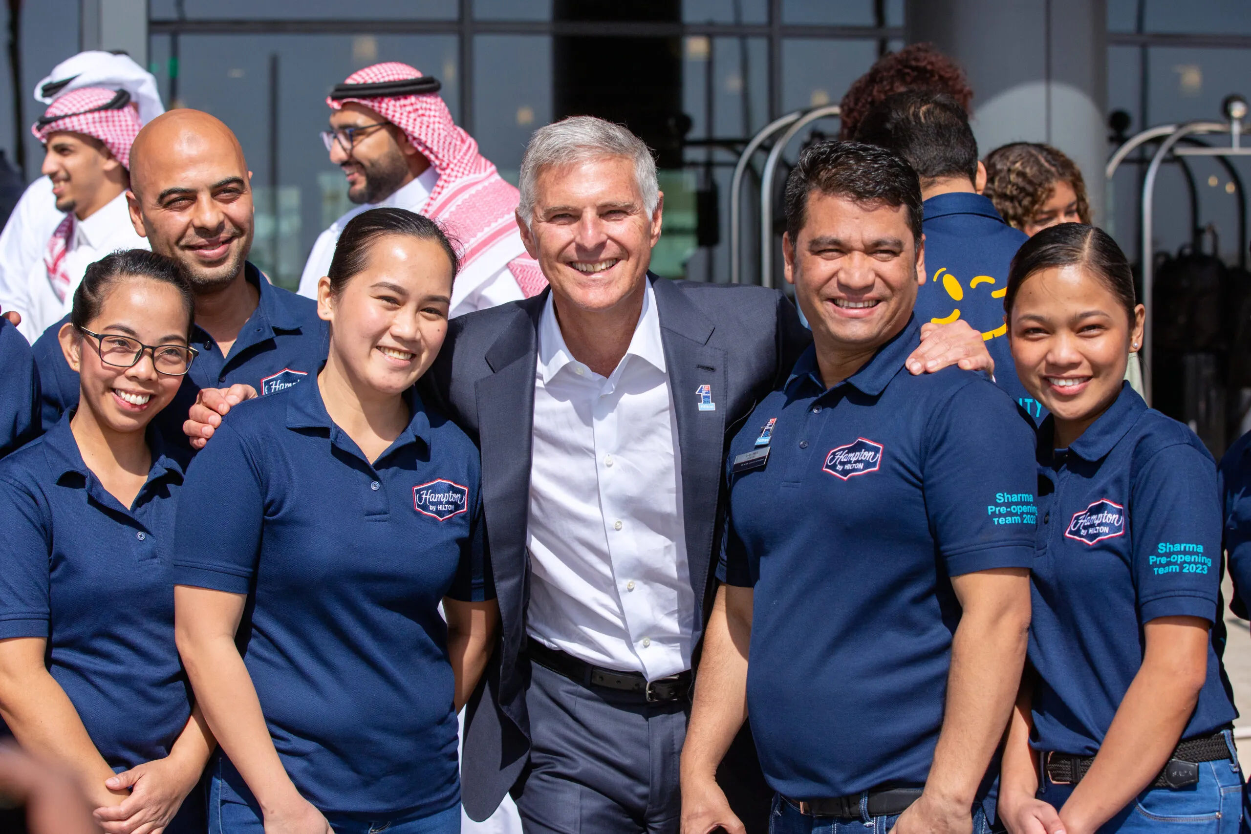 An executive posing arm-in-arm with members of the hotel pre-opening team
