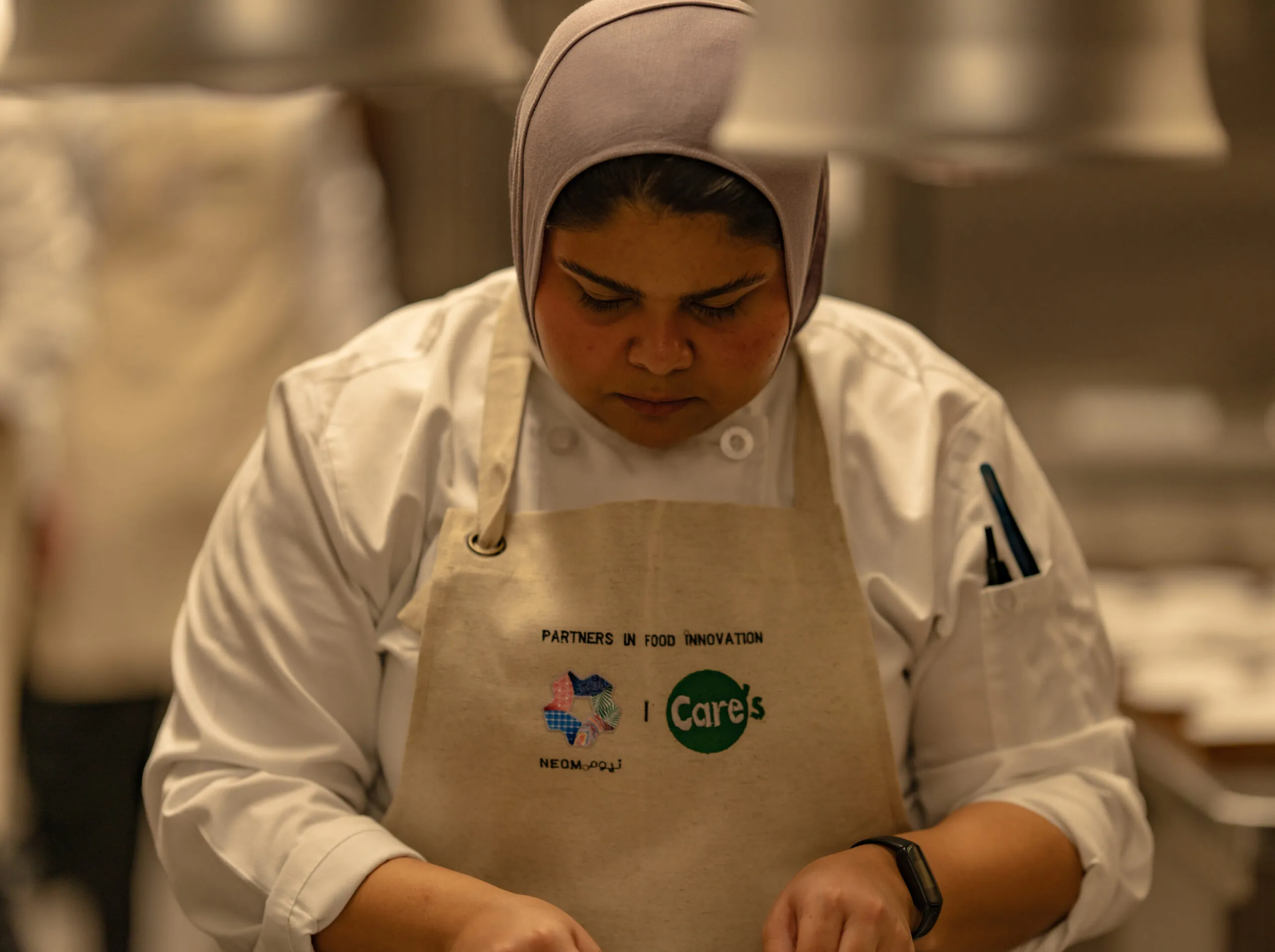 A chef in a 'Partners in Food Innovation' apron at work in the kitchen