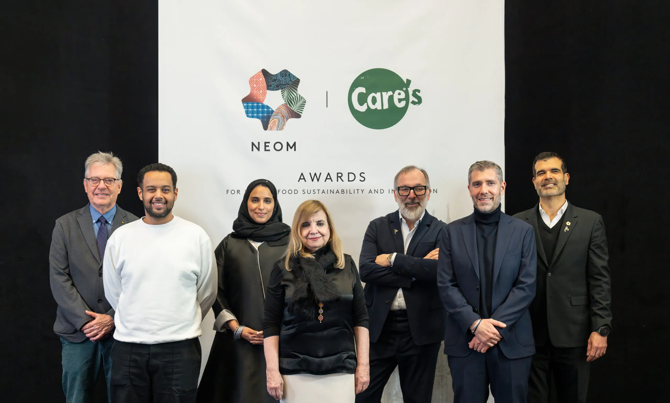 Guests and hosts lined up for a photograph before the NEOM and CARE's Awards wall