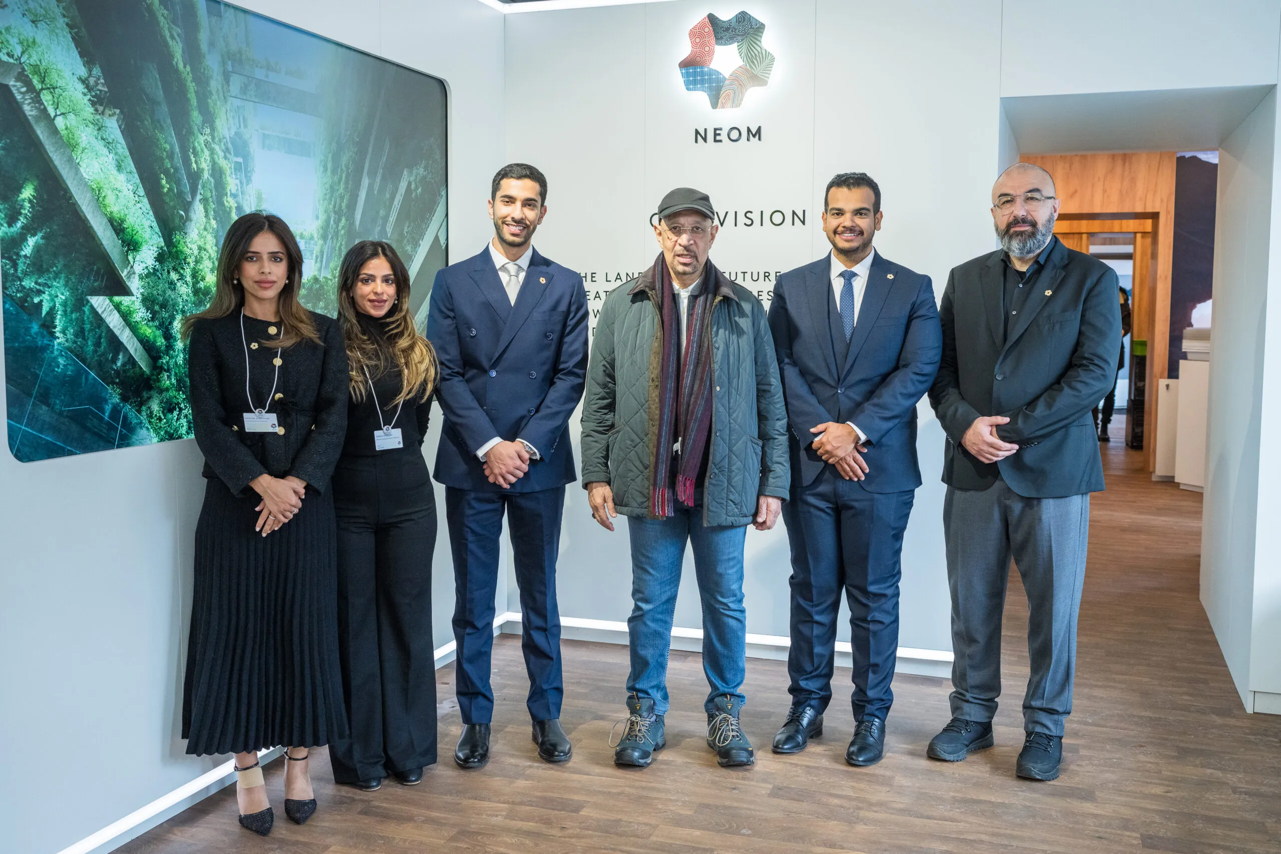 Six guests posing for a photograph beneath the NEOM logo and vision wall
