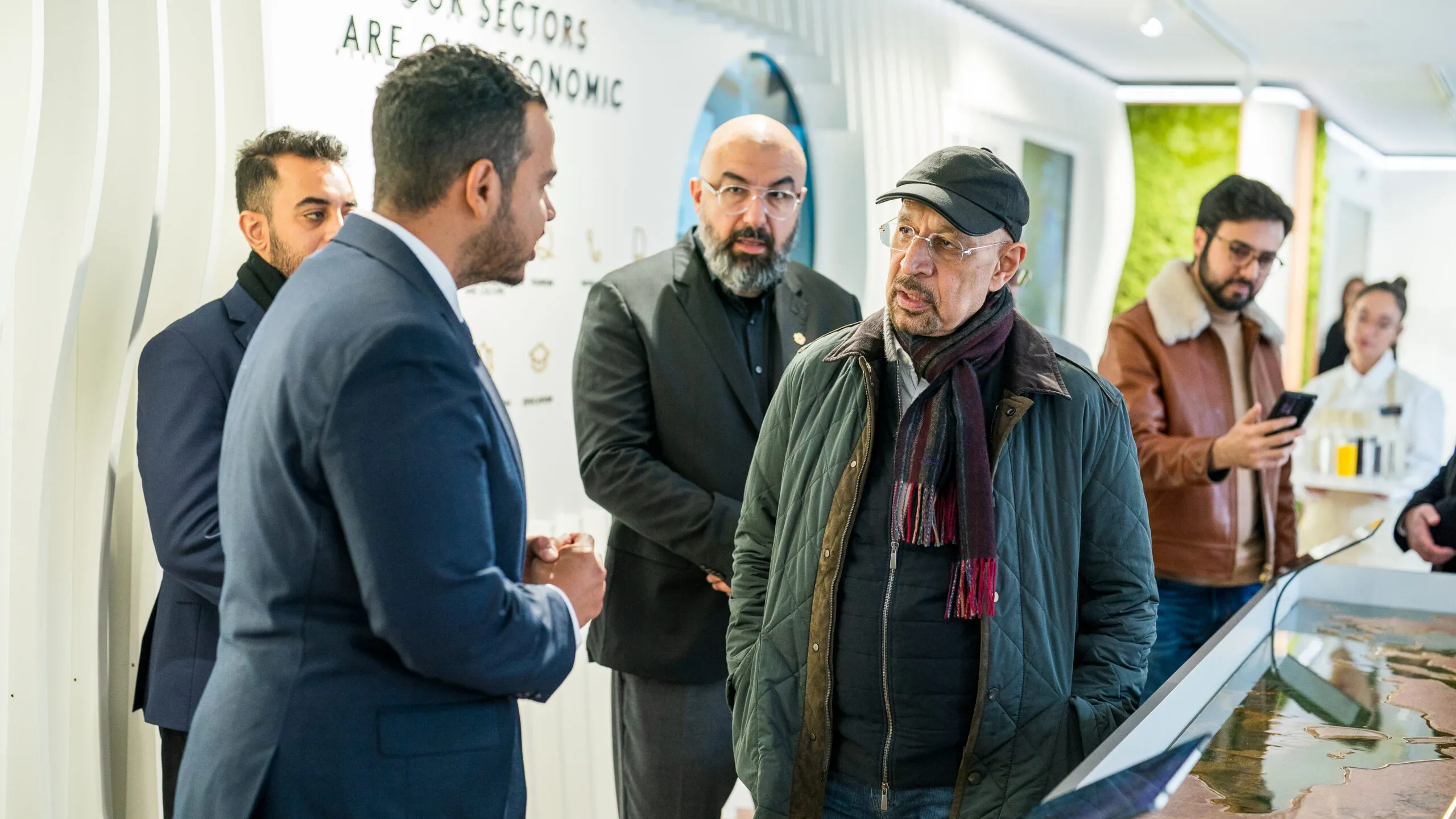 A host in conversation with a group of visitors beside a display table