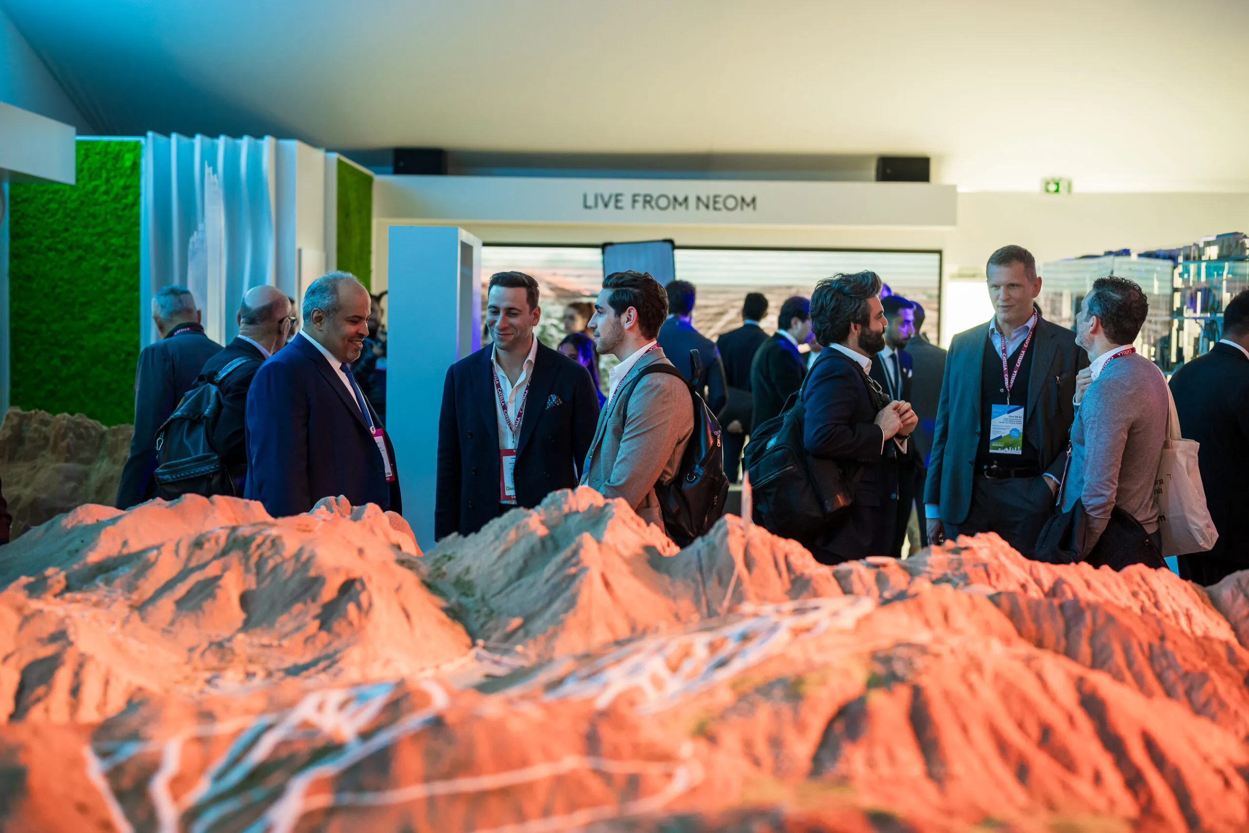 Visitors mingling behind a large terrain model of NEOM's mountains at the stand