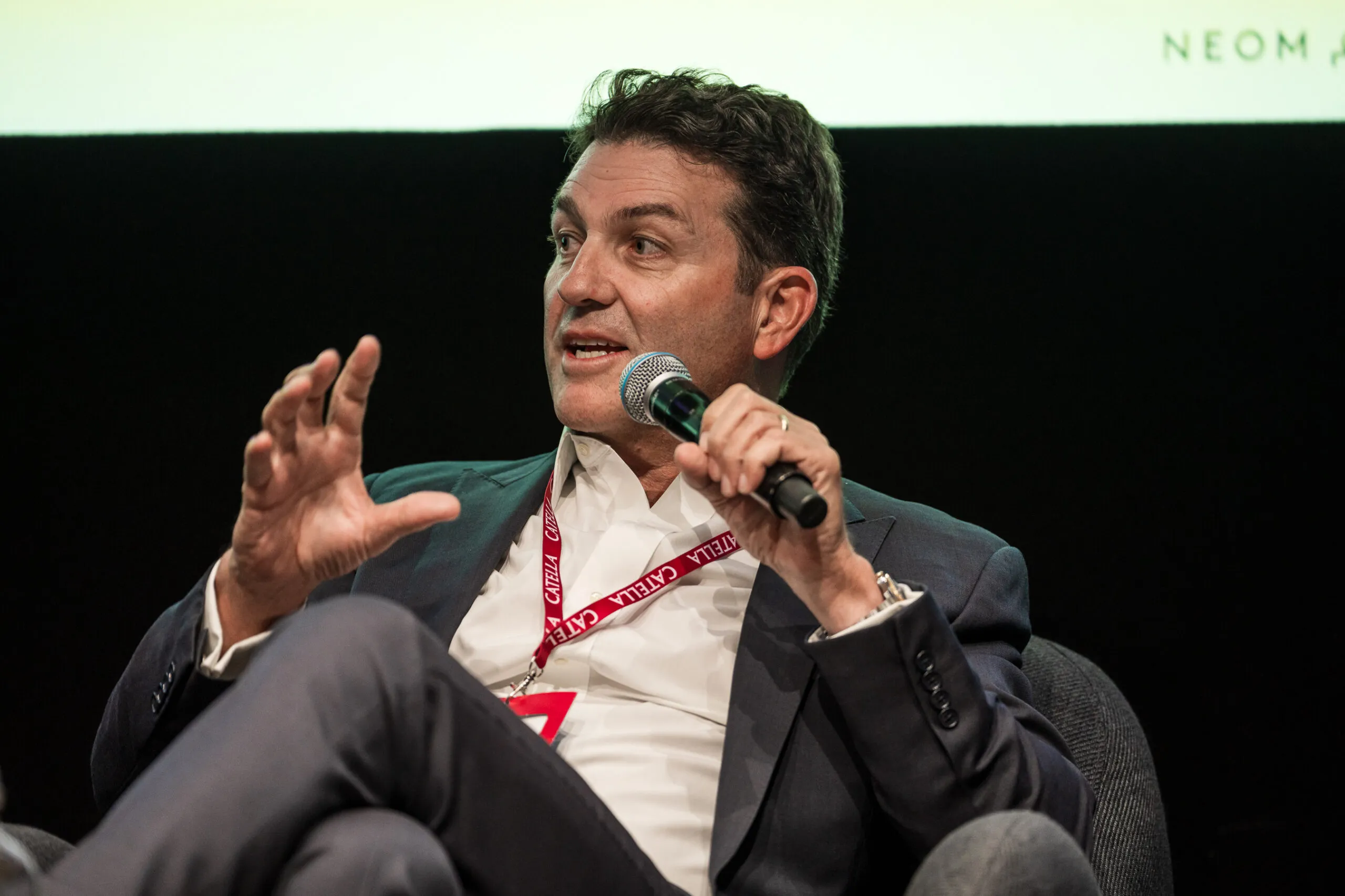 A speaker gesturing as he talks into a microphone during a NEOM session