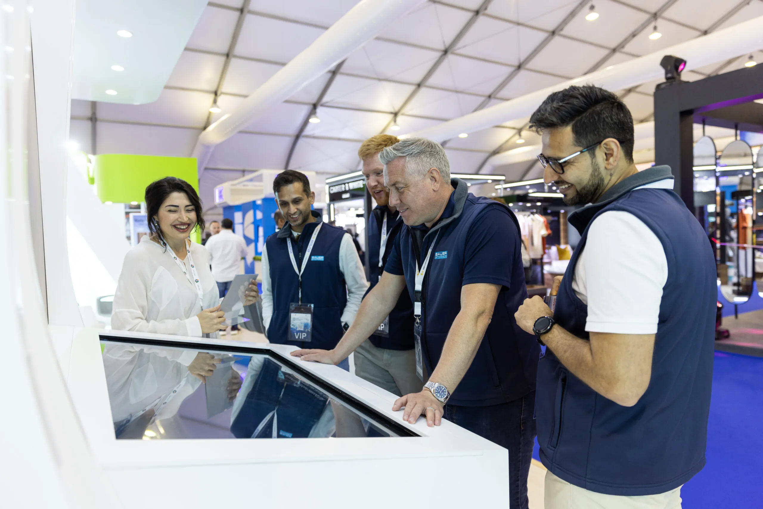Staff and visitors gathered around an interactive touchscreen table on the stand