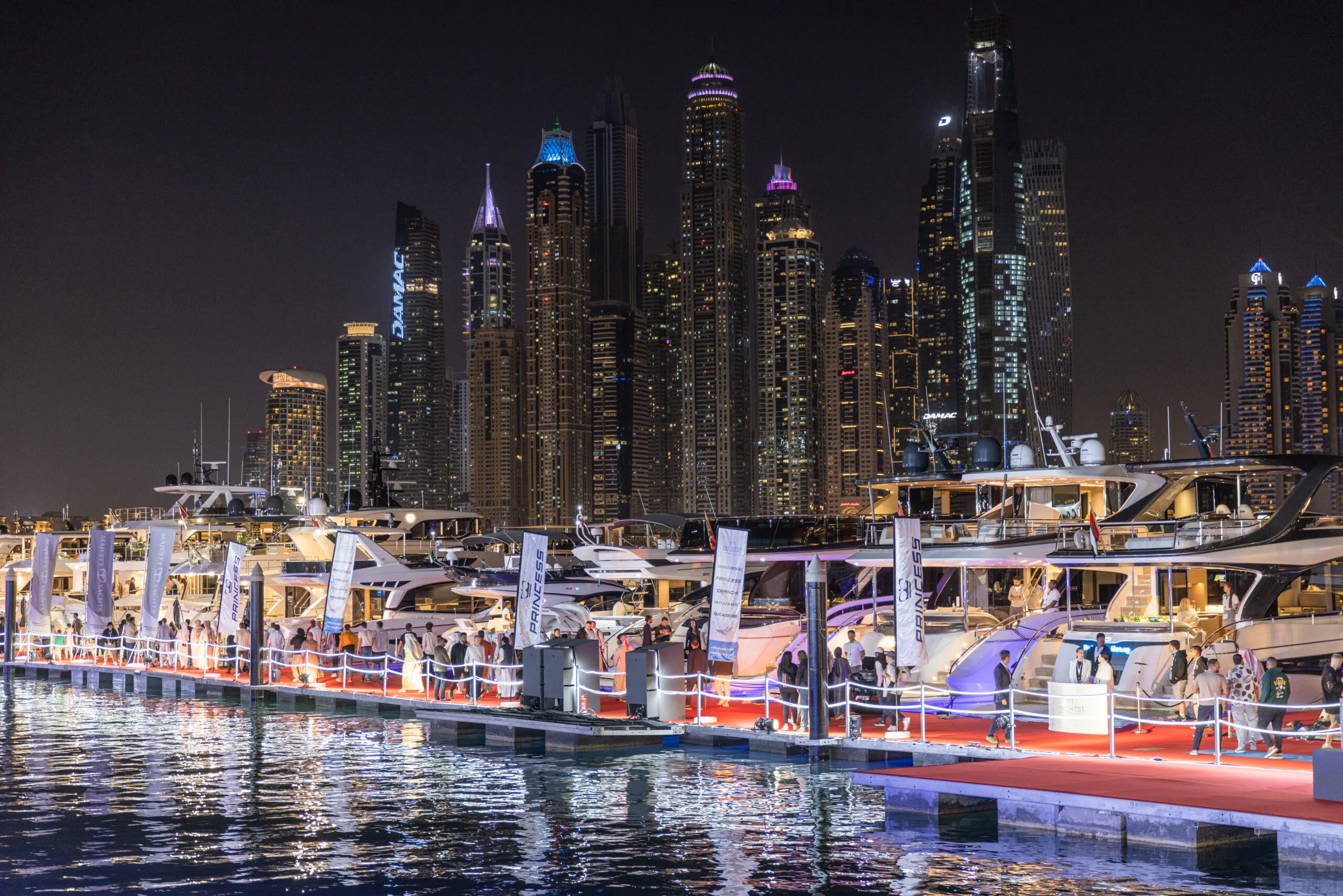 The show marina at night, illuminated yachts against the Dubai Marina skyline