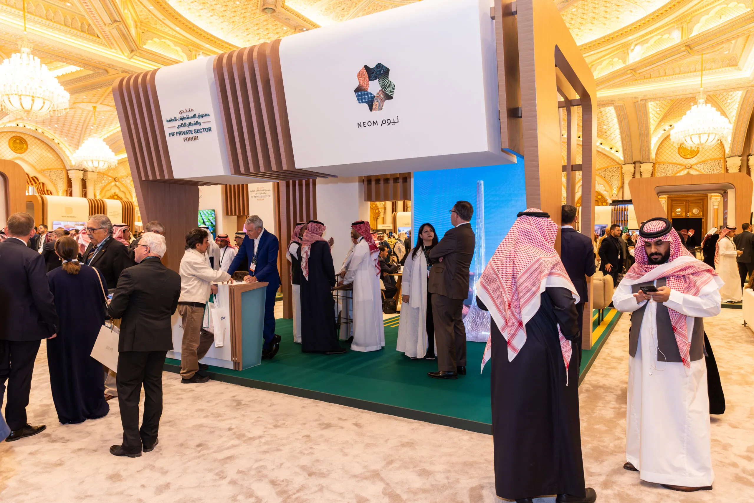 Guests mingling around the NEOM booth beneath the hall's gilded ceiling
