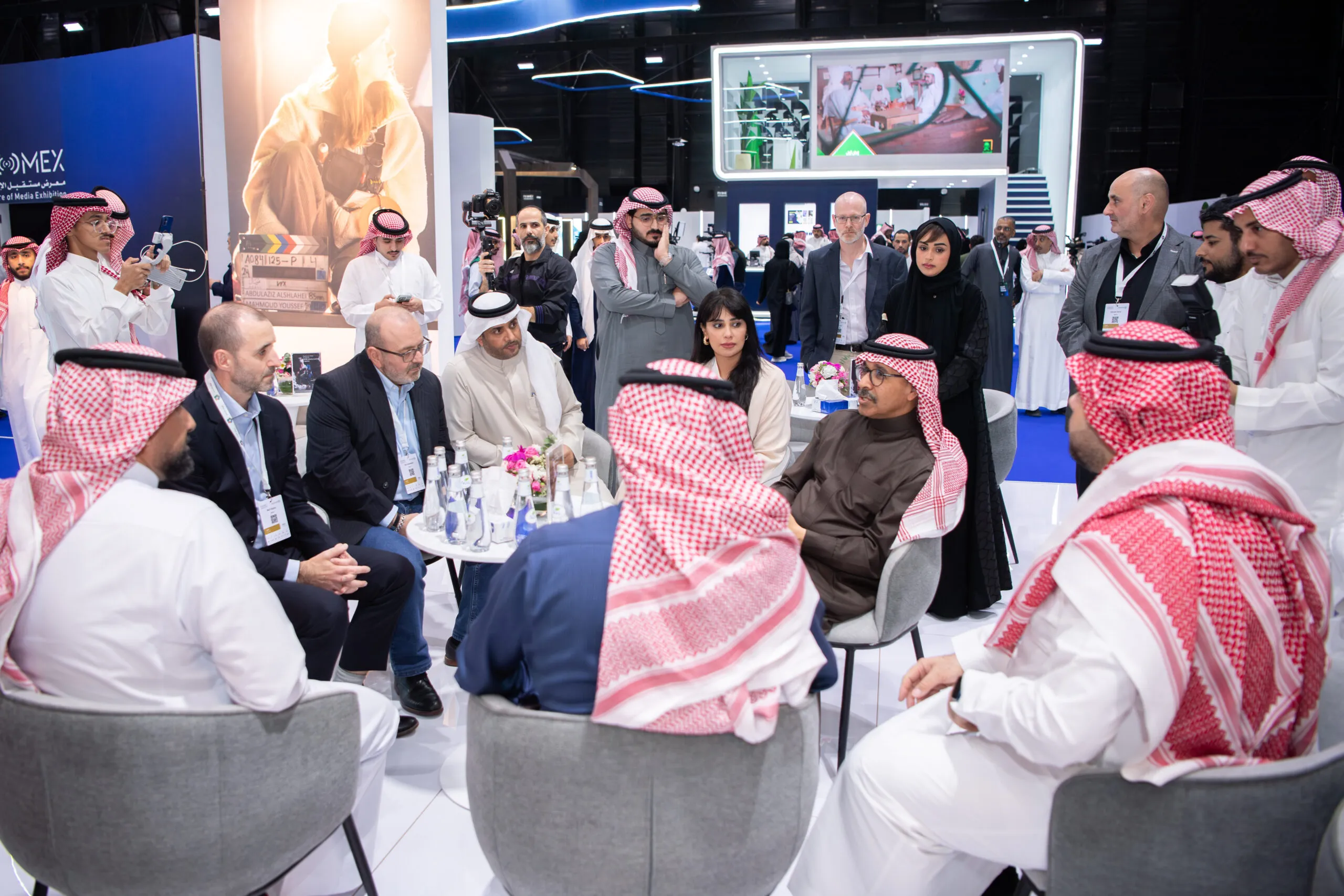 Delegates seated in a circle of armchairs, in discussion